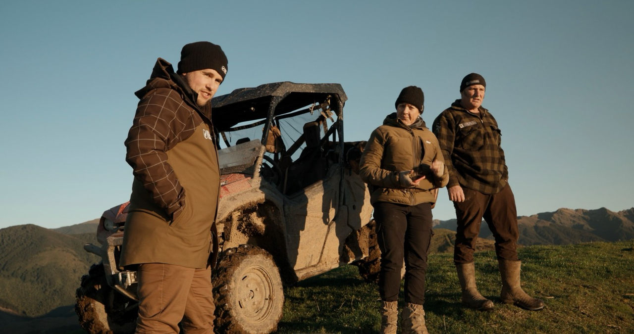 Ryan MacArthur on farm on a clear morning, standing in front of a side by side with farmers Lynley and Matt Wyeth